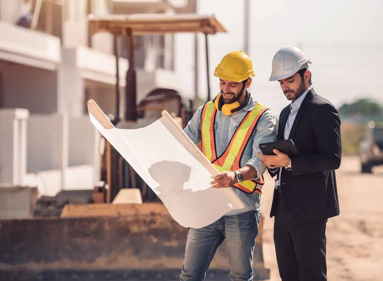 مهندس وموظف موقع يراجعان مخططات مشروع إنشائي